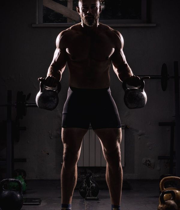 Man performing a focused exercise in a dark gym environment